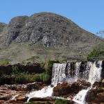 Cachoeira desliza por um paredão rochoso na Serra do Cipó, em meio à vegetação natural.