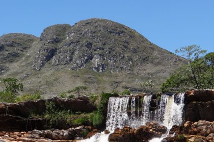 Cachoeira desliza por um paredão rochoso na Serra do Cipó, em meio à vegetação natural.