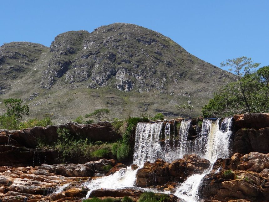 Cachoeira desliza por um paredão rochoso na Serra do Cipó, em meio à vegetação natural.