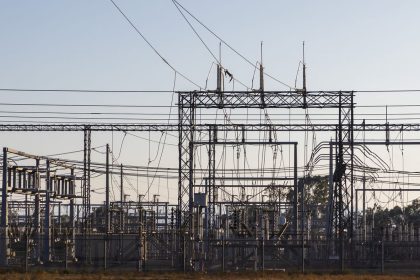 Subestação elétrica de alta tensão com estruturas metálicas e linhas de transmissão ao amanhecer
